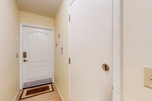 A hallway with a white door, a doormat, and a light switch on the wall. - Ocean-view townhome with balcony & W/D - walk to beach - dog-friendly (Jacksonville Beach)