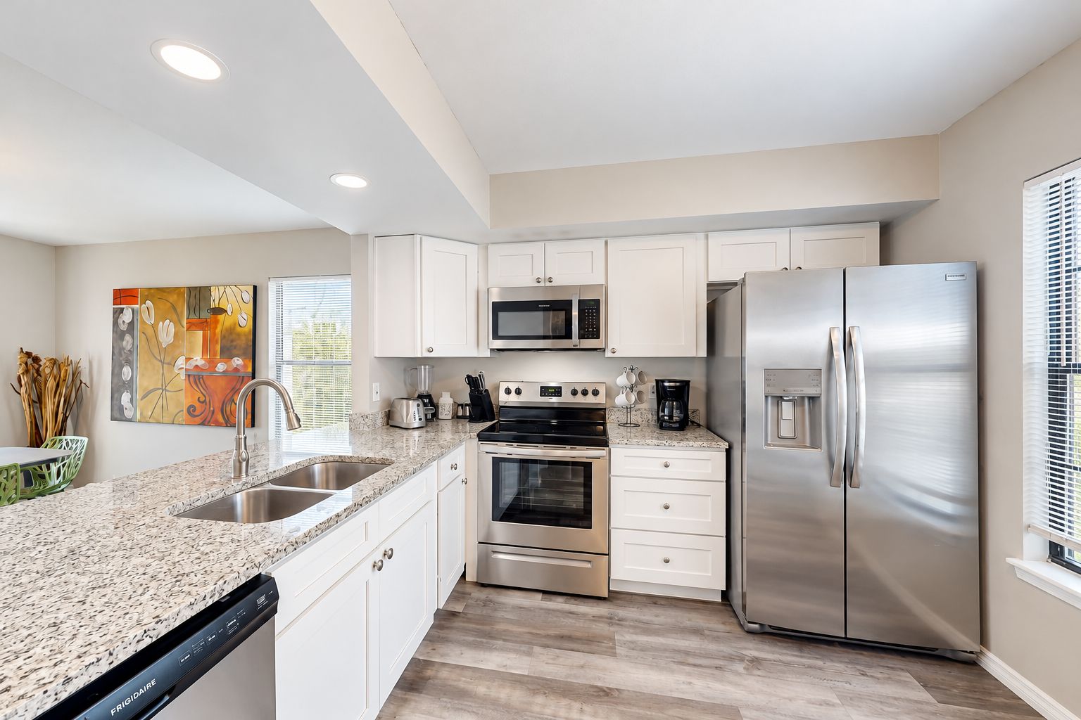 A modern kitchen with white cabinetry, stainless steel appliances, and a granite countertop.
