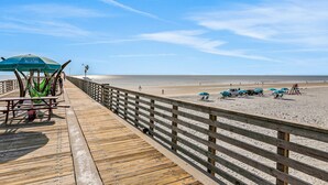 A wooden pier with picnic tables and umbrellas, leading to a sandy beach with umbrellas and beach chairs. - Cozy Spacious Home with Private Backyard and Patio, near shopping (Jacksonville)