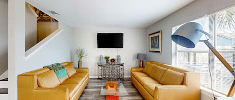 A living room with two yellow sofas, a coffee table, a TV, and a lamp.