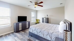 A bedroom with a bed, dresser, TV, and ceiling fan. - Cozy Spacious Home with Private Backyard and Patio, near shopping (Jacksonville)