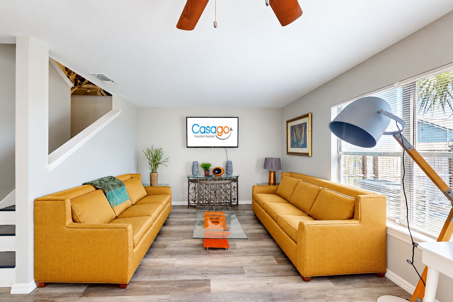 Una sala de estar moderna con dos sofás, una mesa de centro, un televisor y un letrero de Casago Vacation Rentals.