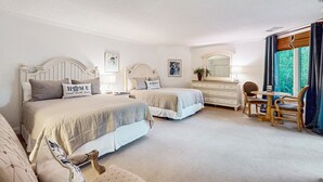 Un dormitorio con dos camas, un tocador, una silla y una ventana con cortinas.