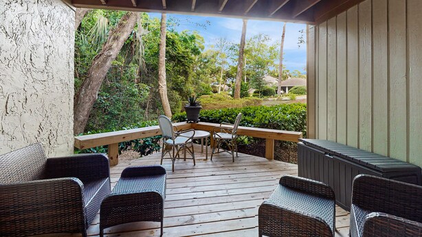 Una terraza cubierta con mobiliario de mimbre, una mesa y una planta en maceta.