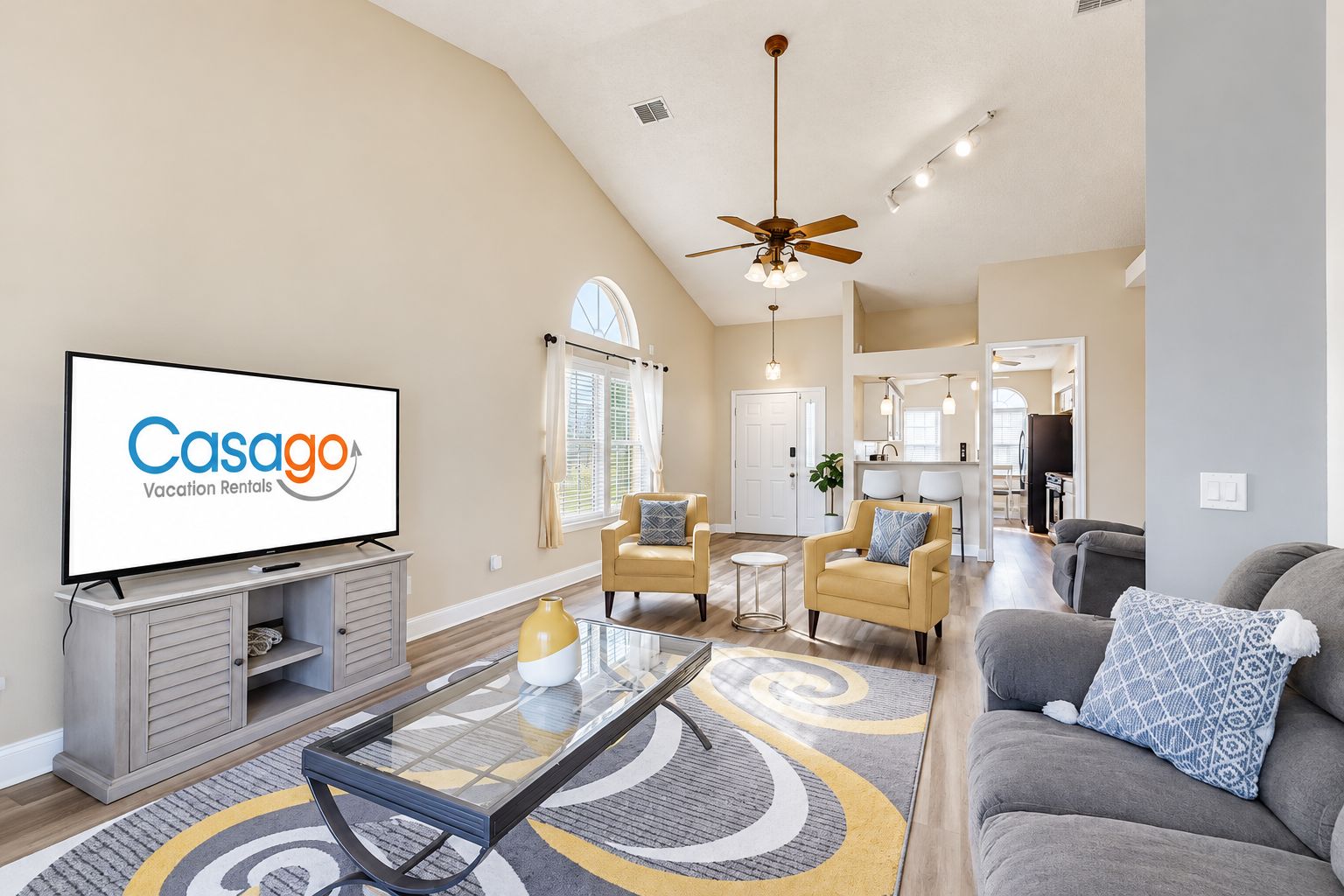 A spacious living room with a flat-screen TV, a ceiling fan, and a dining area with chairs.