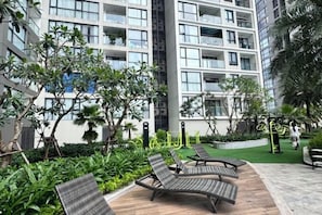 Une cour intérieure avec des fauteuils, de la verdure et un bâtiment doté de balcons.