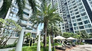 A high-rise building with a pool area, including lounge chairs and umbrellas. - Hopo Housing - Vinhomes Skylake Apartment Luxury Hanoi (Hanoi)