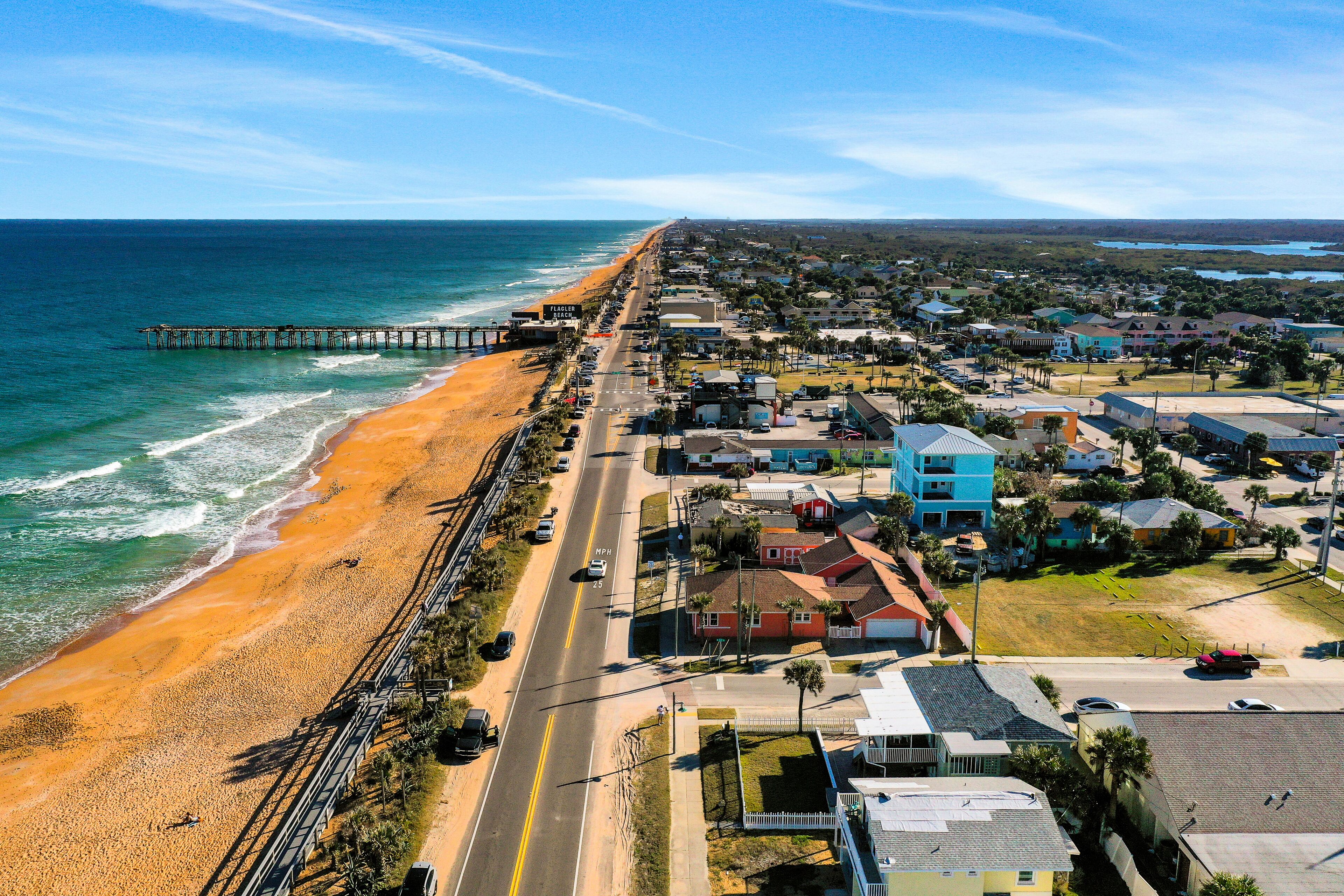 Une ville côtière dotée d’une plage, d’une jetée et d’immeubles d’habitation le long de la côte.