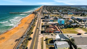 A coastal town with a beach, a pier, and residential buildings along the shore.