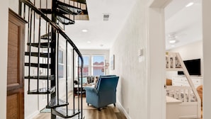 A modern interior with a spiral staircase, a blue armchair, and a white dresser.