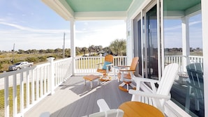 A covered porch with white railings, outdoor furniture, and a view of the landscape. - Stylish brand-new ocean view home with deck & porch - steps to beach (Palm Coast)