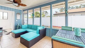 A covered patio with wicker furniture, a ceiling fan, and large windows. - Water-view dog-friendly home with outdoor space & entertainment options (Palm Coast)