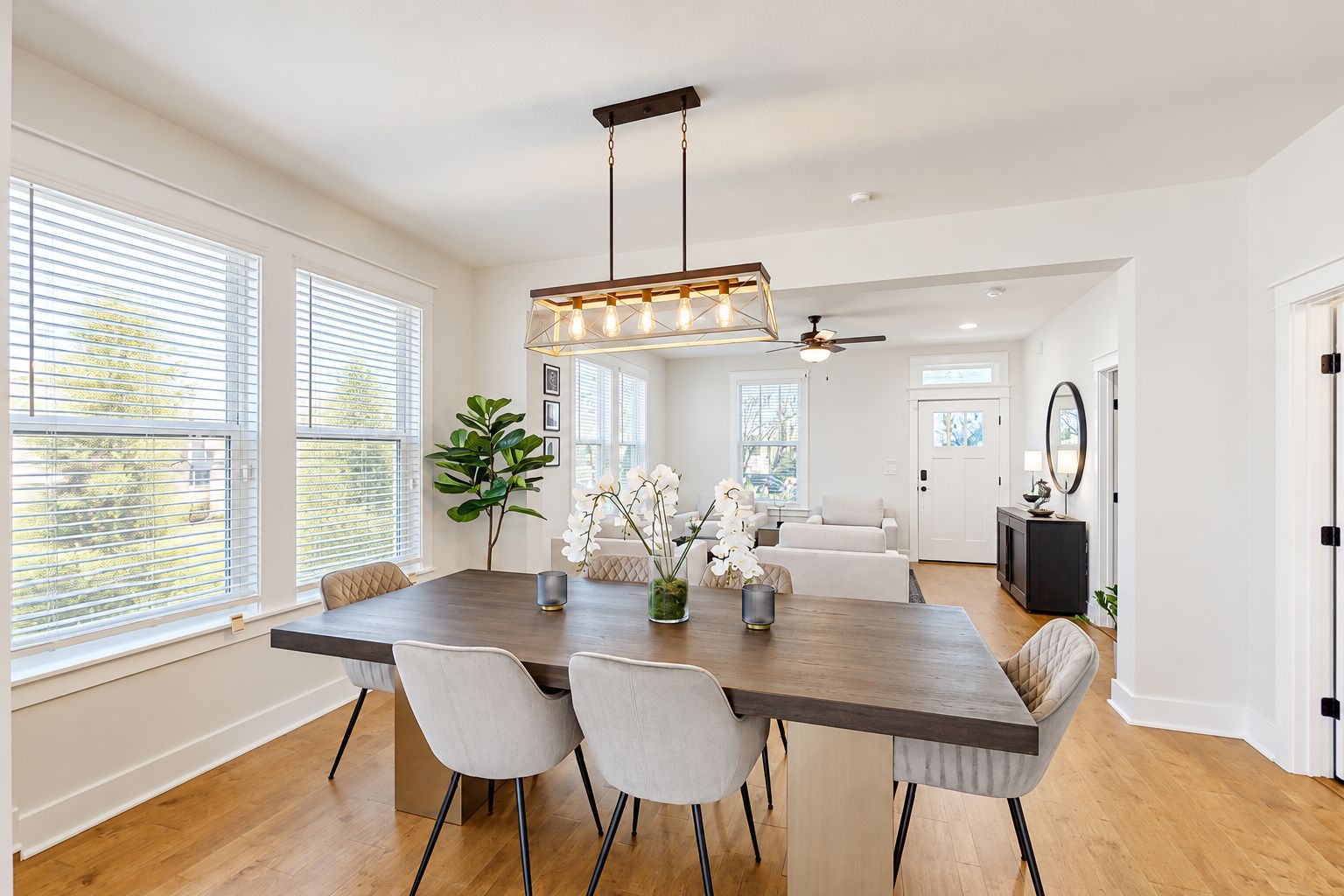 A spacious dining area with a long table, chairs, and a modern chandelier.