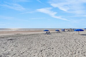 Une plage de sable avec des parasols bleus et des chaises longues.