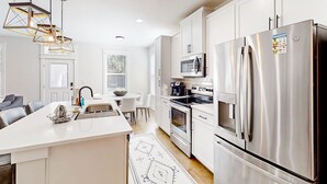 A modern kitchen with white cabinets, stainless steel appliances, and a central island. - Brand new home with open layout, office, & great location - dog-friendly (Jacksonville)