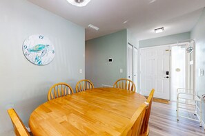 Un comedor con una mesa y sillas de madera, un reloj de pared y una puerta con reja metálica.