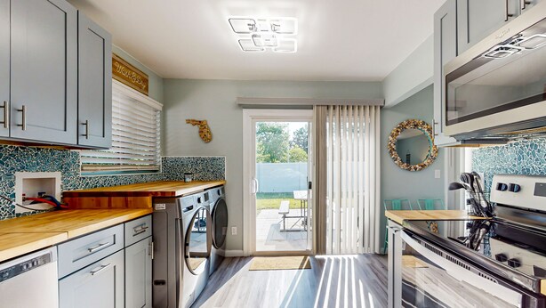 A modern kitchen with grey cabinets, a built-in oven, and a washing machine.
