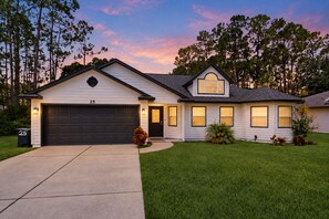 A two-story house with a garage, a well-maintained lawn, and a driveway. - Home near the beach with private pool, inviting patio, streaming & AC (Palm Coast)