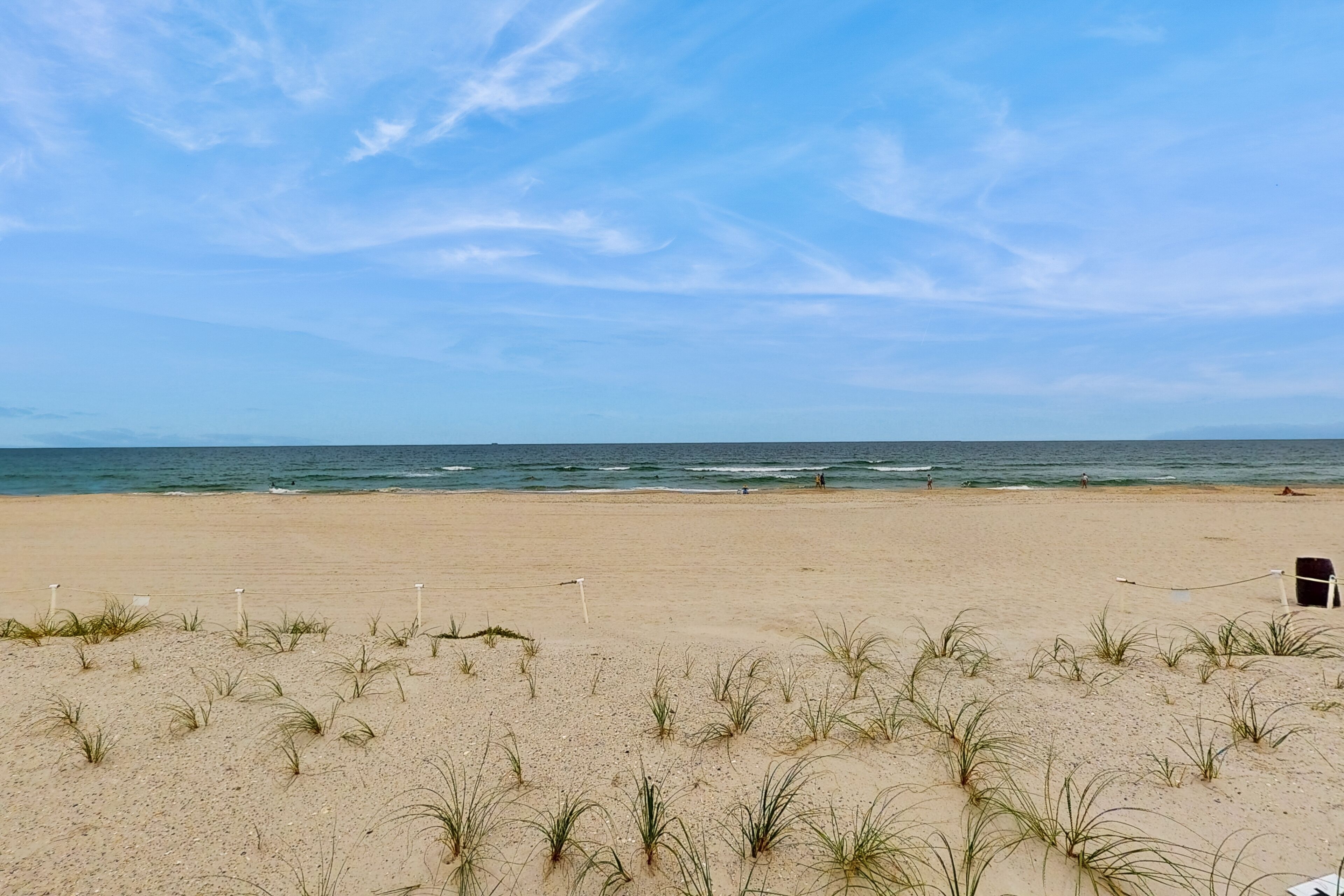 Een strand met duinen en een heldere lucht.