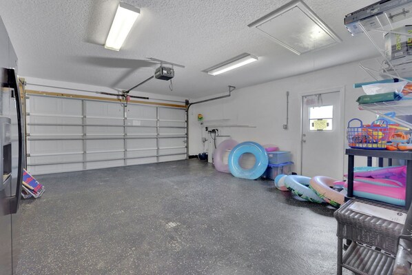 Un garage avec une porte blanche, un projecteur fixé au plafond et des anneaux gonflables sur le sol.