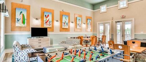 A room with a foosball table, a TV, and artwork on the walls.