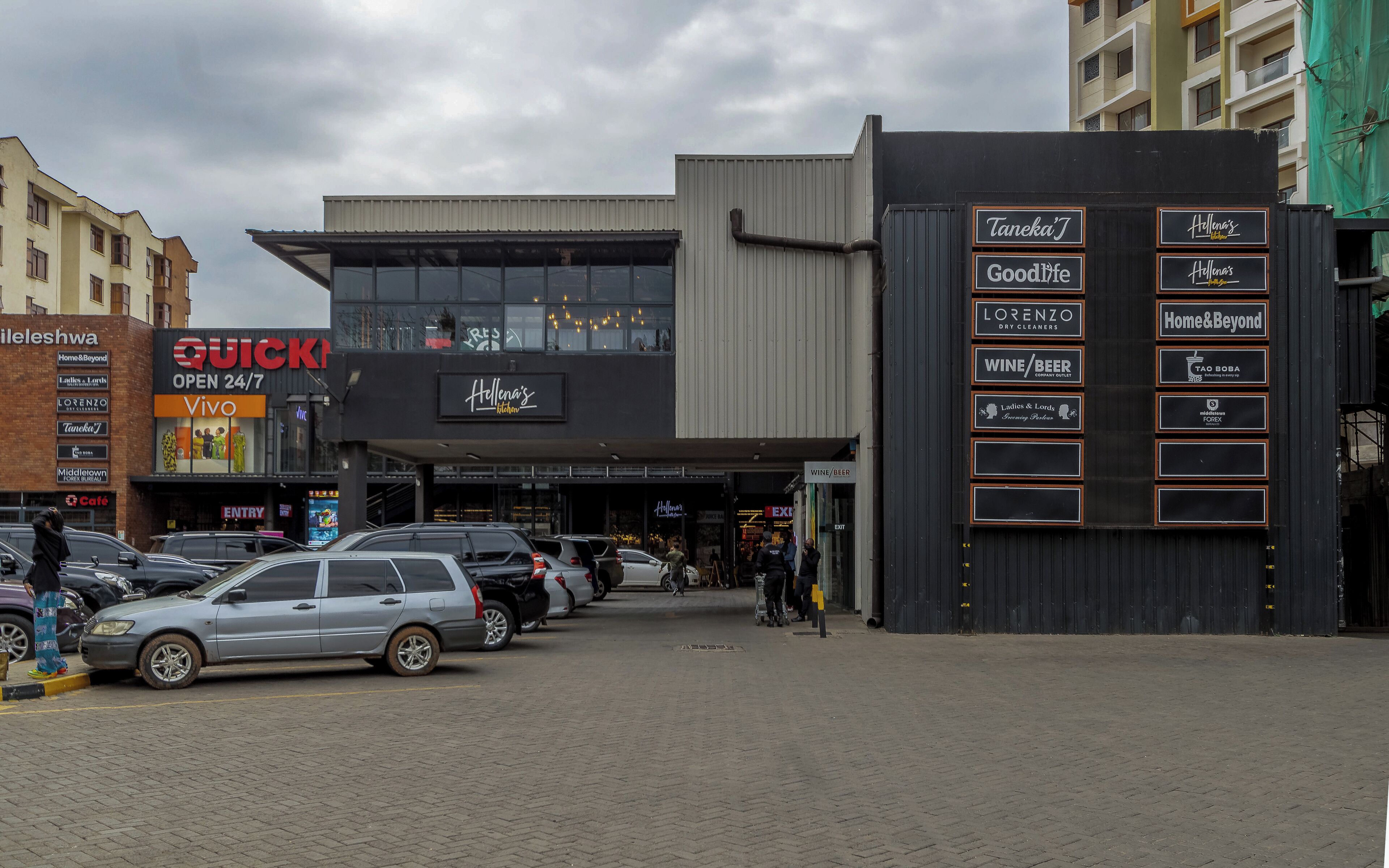 Un edificio comercial con varias fachadas, que alberga una tintorería, una licorería y un café.