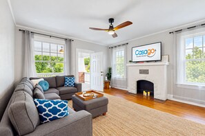A living room with a grey sofa, a flat-screen TV, a fireplace, and a ceiling fan. - Spacious duplex with private balcony, washer & dryer, and WiFI (Jacksonville)