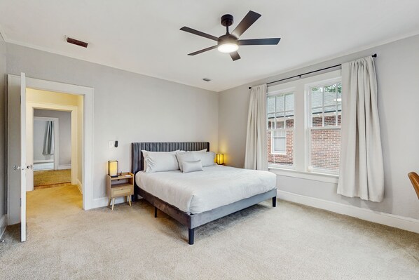 A bedroom with a bed, bedside lamps, a ceiling fan, and a window with curtains. - Spacious duplex with private balcony, washer & dryer, and WiFI (Jacksonville)