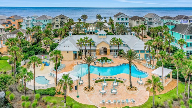 Un resort con una gran piscina, palmeras y vista al océano.