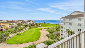 Campo de golf con vistas al océano y edificios cercanos.