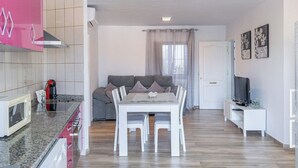 A modern living space with a kitchen, dining area, and a seating area with a sofa and TV. - Casa Loli Frigiliana by Ruralidays (Málaga)