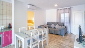A compact living space with a dining area, a sofa, and a television. - Casa Loli Frigiliana by Ruralidays (Málaga)