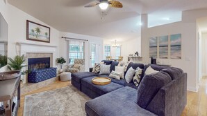 A spacious living room with a fireplace, a large sectional sofa, and a ceiling fan. - Spacious Home with Private Pool,Spa, Gas Grill and Patio (Palm Coast)