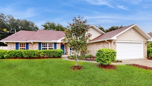 A two-story house with a brick facade, a red-tiled roof, and a front garage. - Spacious Home with Private Pool,Spa, Gas Grill and Patio (Palm Coast)