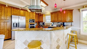 A kitchen with wooden cabinets, a stainless steel refrigerator, a built-in oven, and a granite countertop.