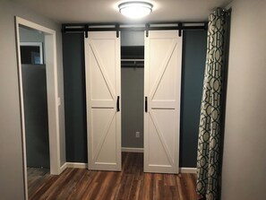 Un pasillo con un armario de puerta corredera, una cortina estampada y suelo de madera.