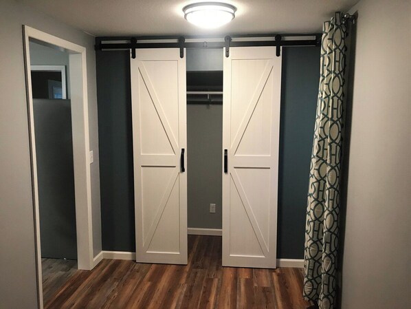 A hallway with a sliding door closet, a patterned curtain, and a wooden floor.