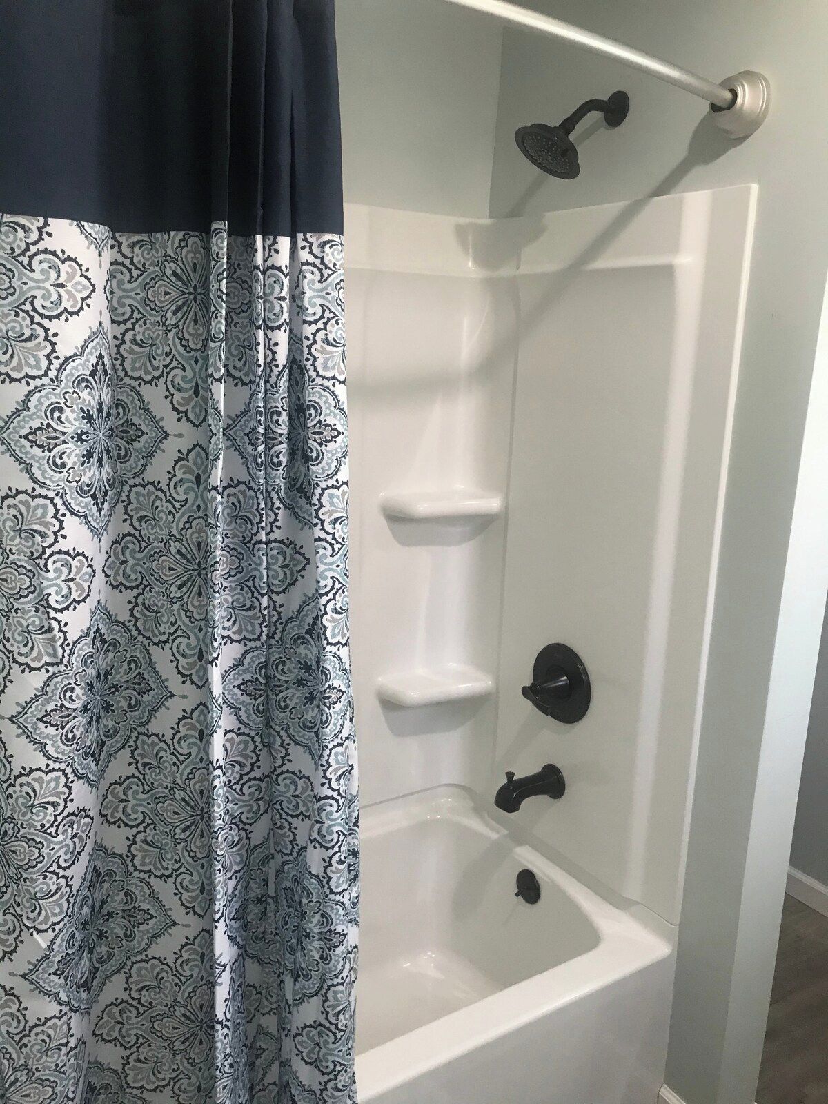 A bathroom with a shower, a white sink, and a towel rack.