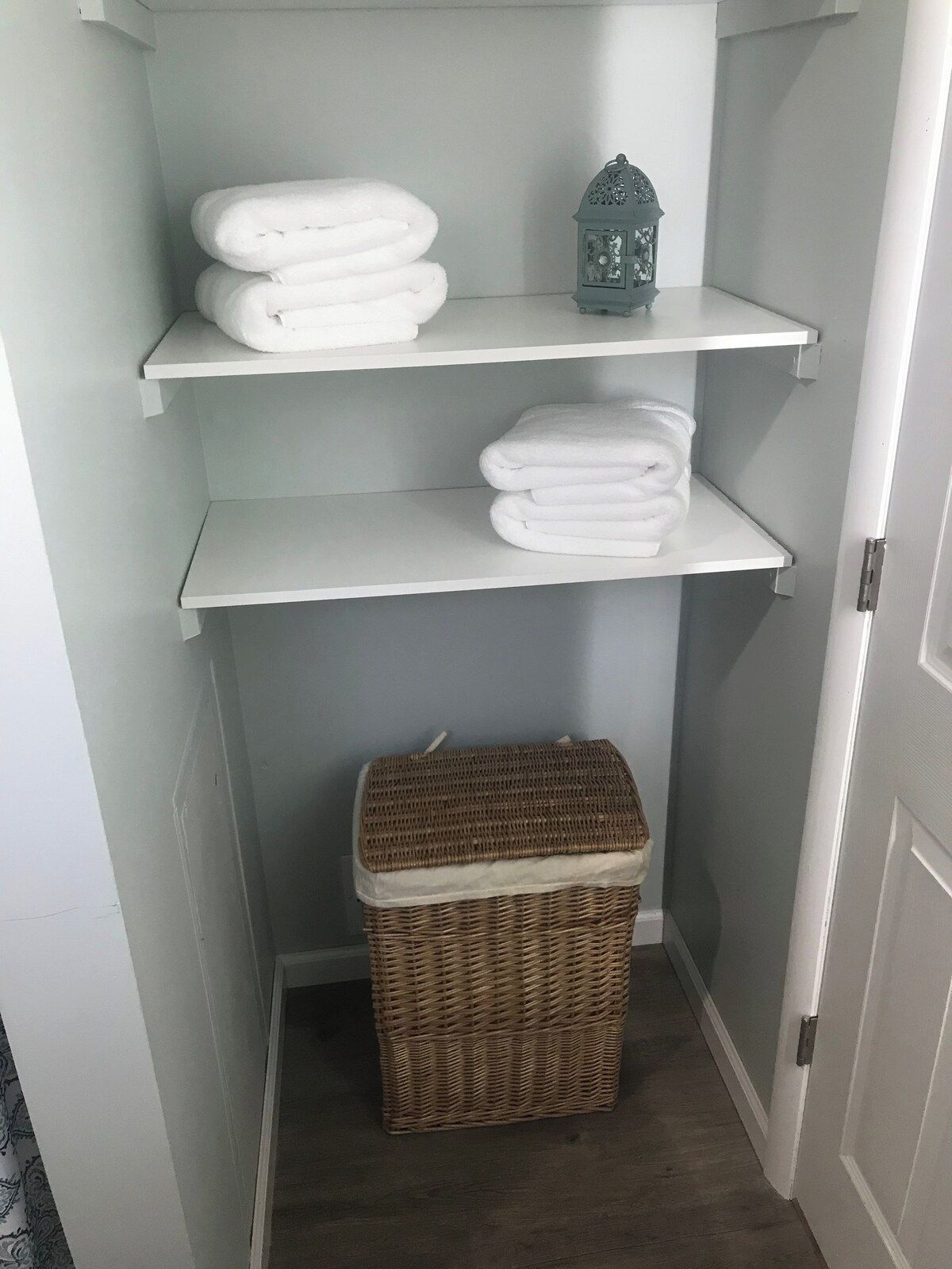 A storage area with shelves holding folded towels and a decorative lantern.