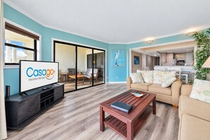 A modern living room with a flat-screen TV, a wooden coffee table, and a sofa with patterned cushions. - Beautiful Home Near the Beach with Views of the Atlantic off the Private Balcony (St. Augustine)