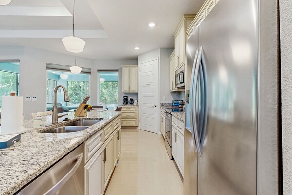 A modern kitchen with granite countertops, stainless steel appliances, and a view of the outdoors. - Spacious house with private covered patio, work station, full kitchen and grill (Palm Coast)