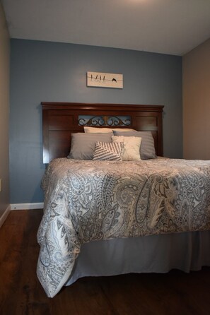 A bedroom with a bed, a headboard, and a wall-mounted sign.