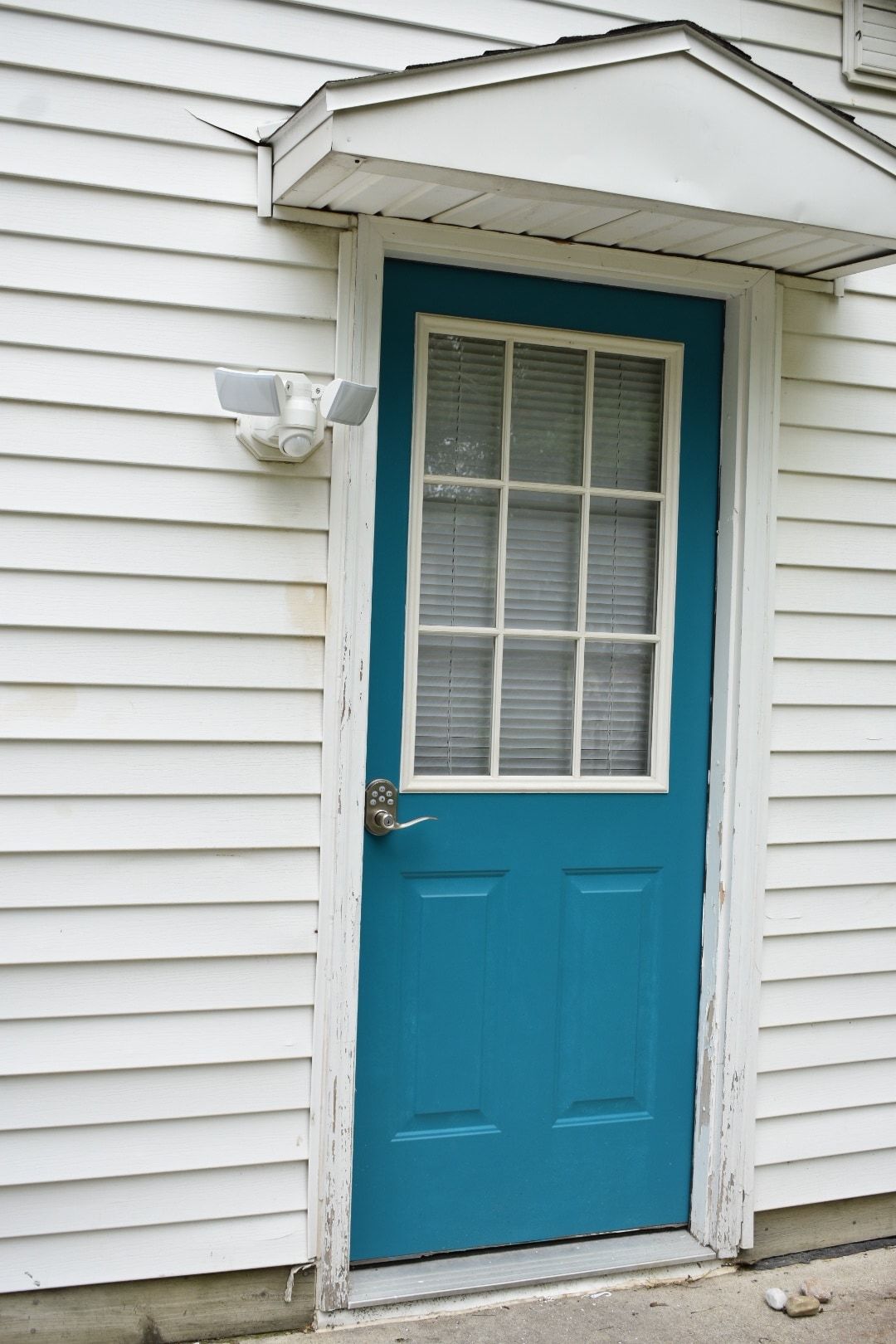 Une maison blanche avec une porte bleue et une fenêtre blanche.