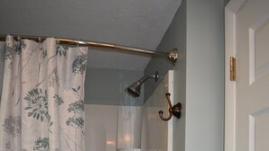 Une douche avec un rideau à motifs floraux, un pommeau de douche et un porte-serviettes.