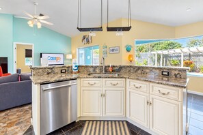 A kitchen with white cabinets, granite countertops, and a built-in dishwasher.