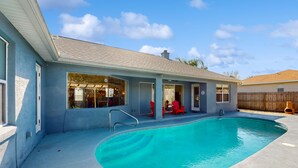Ein Garten mit Pool, überdachter Terrasse und Holzzaun im Hintergrund.