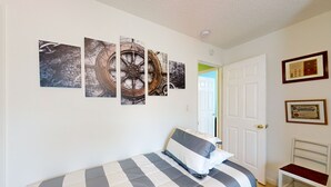 A bedroom with a bed, a chair, and a door. - Spacious Pet -Friendly Home w/ Fenced in Yard and Close to The Beach (St. Augustine)