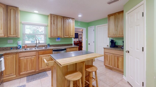 A kitchen with wooden cabinets, a stainless steel countertop, and a bar stool area. - Spacious Pet -Friendly Home w/ Fenced in Yard and Close to The Beach (St. Augustine)