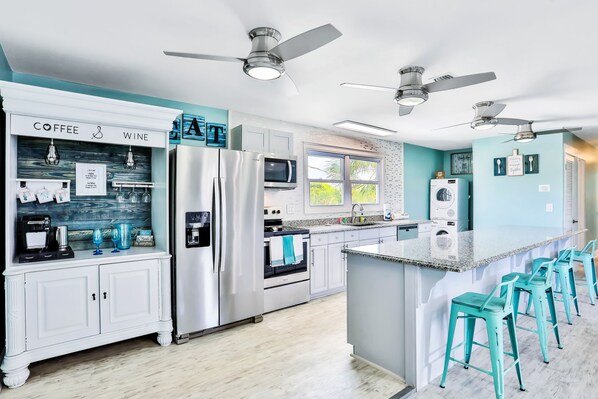 A modern kitchen with stainless steel appliances, a coffee station, and teal accents. - Home 1 Block from 2 Beaches w/Private Pool, High-Speed WiFi & Central AC (St. Augustine)