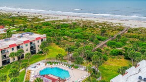 Un hotel con piscina, vistas a la playa y exuberante vegetación.